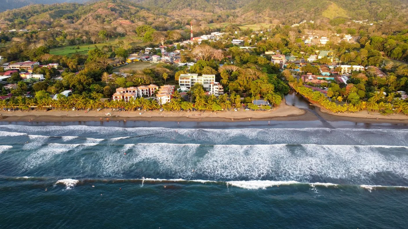 Aerial photograph of Jacó Beach, Costa Rica, showing the Pacific coastline and coastal town.